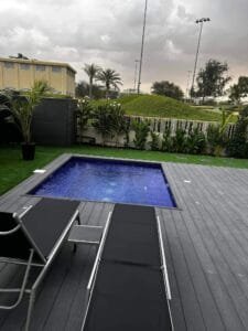 Completed swimming pool with dark tile finish and grey composite decking, Dubai Hills Estate villa